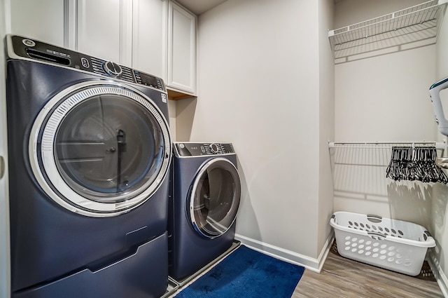 clothes washing area with cabinet space, independent washer and dryer, baseboards, and wood finished floors