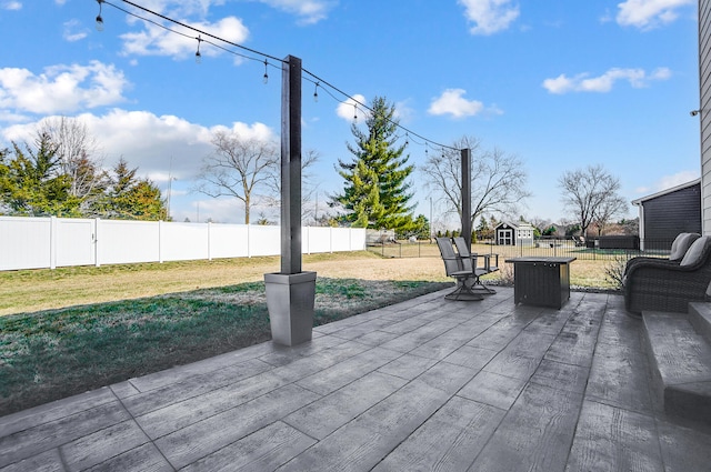 view of patio with an outbuilding, a storage unit, and a fenced backyard