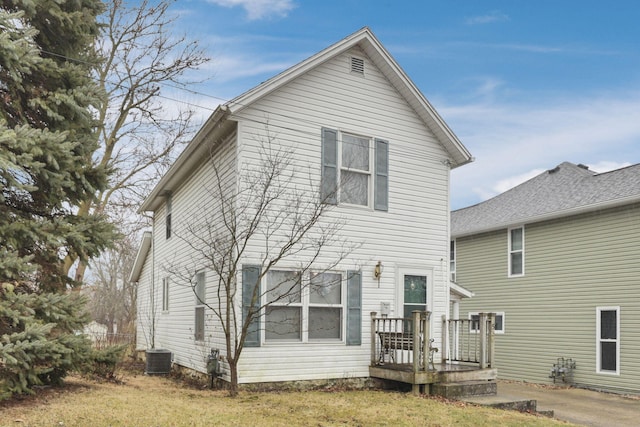 rear view of house featuring cooling unit and a lawn