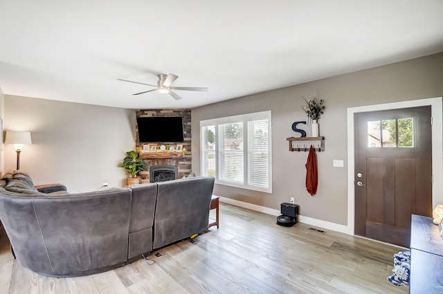 living room featuring ceiling fan, a fireplace, and light hardwood / wood-style floors