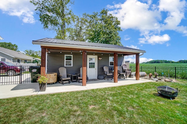 back of property with a patio, a yard, and a fire pit