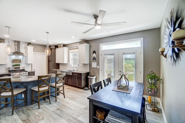 dining space with french doors, ceiling fan, light hardwood / wood-style floors, and sink