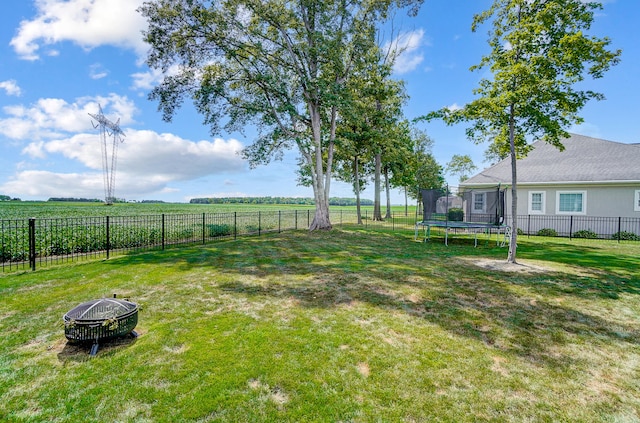 view of yard featuring a trampoline, a fire pit, and a rural view