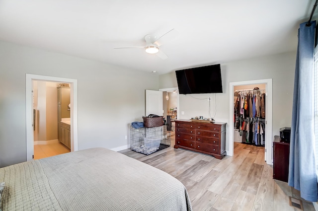 bedroom with connected bathroom, a spacious closet, light wood-type flooring, a closet, and ceiling fan