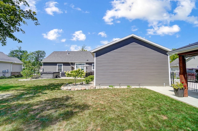 rear view of property with a yard, a hot tub, and a patio