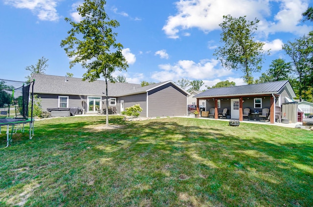 rear view of house featuring a hot tub, a patio, a yard, and a trampoline