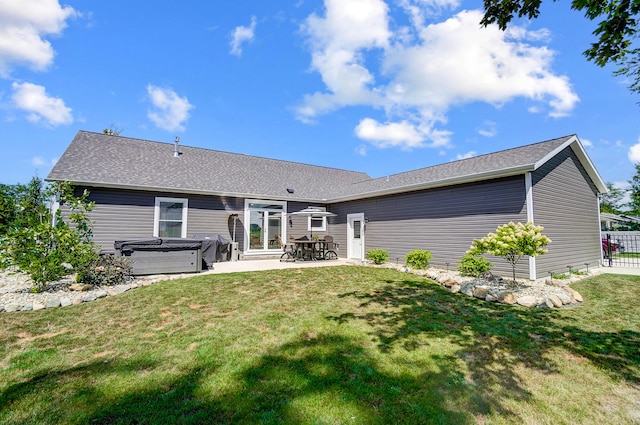 back of house with a hot tub, a lawn, and a patio area