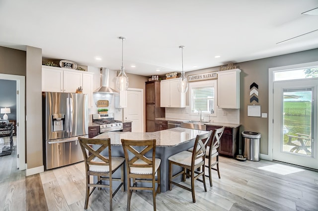 kitchen featuring wall chimney exhaust hood, tasteful backsplash, decorative light fixtures, a kitchen island, and stainless steel appliances