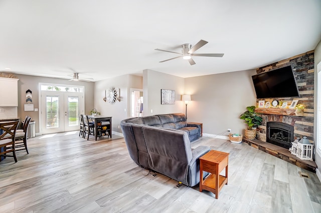 living room with light hardwood / wood-style flooring, a fireplace, french doors, and ceiling fan