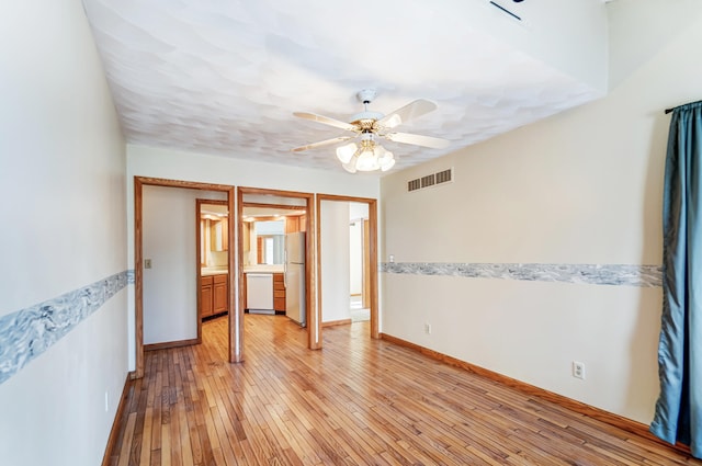 unfurnished room with light wood-style floors, visible vents, ceiling fan, and baseboards