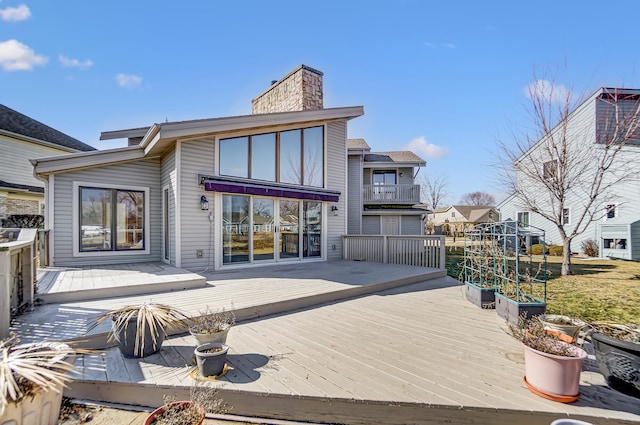 rear view of property featuring a chimney and a wooden deck