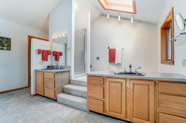 full bathroom featuring carpet floors, vaulted ceiling with skylight, two vanities, and a sink