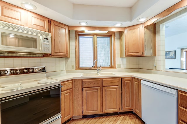 kitchen featuring white appliances, light countertops, a sink, and backsplash