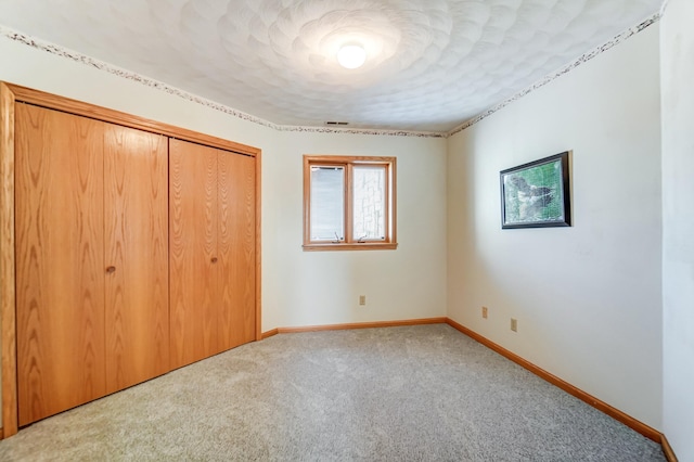 unfurnished bedroom with a closet, carpet flooring, visible vents, and baseboards