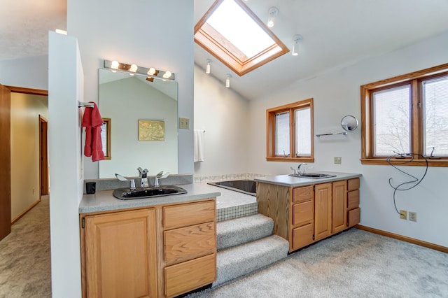 bathroom with lofted ceiling with skylight, two vanities, a sink, and carpet flooring