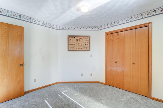 unfurnished bedroom featuring baseboards, a closet, and light colored carpet