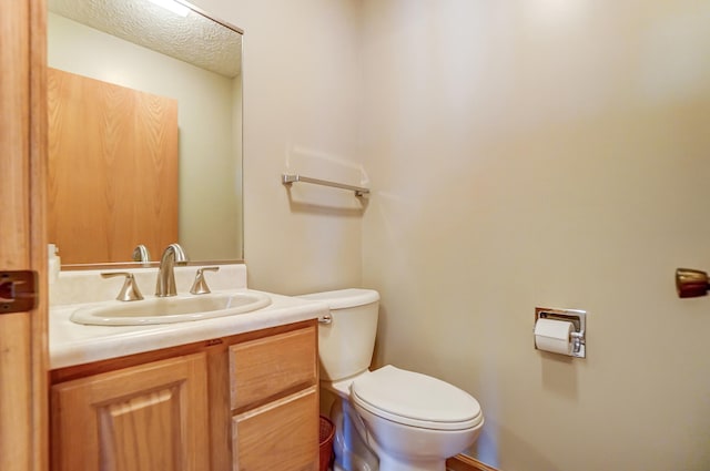 bathroom featuring a textured ceiling, vanity, and toilet