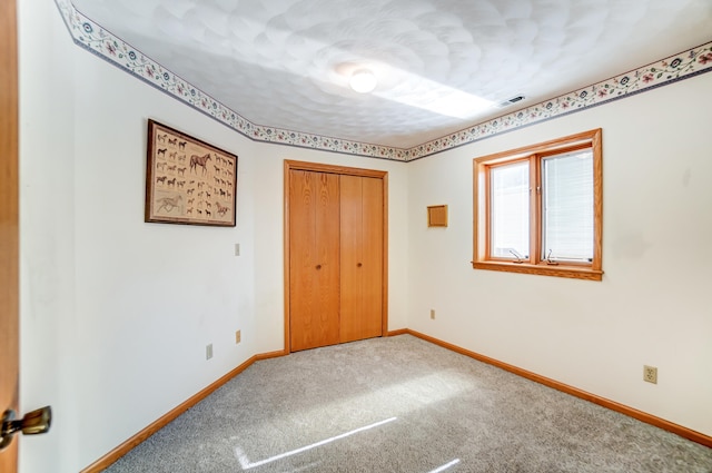 unfurnished bedroom featuring a closet, carpet flooring, visible vents, and baseboards