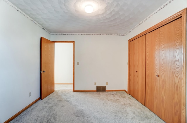 unfurnished bedroom with a closet, light carpet, visible vents, and baseboards