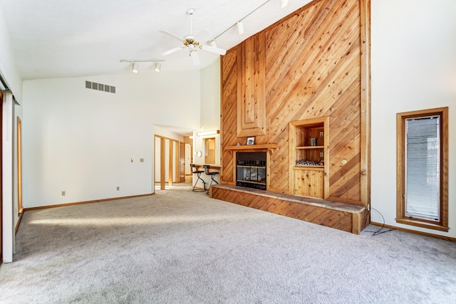 unfurnished living room featuring a ceiling fan, a glass covered fireplace, visible vents, and carpet