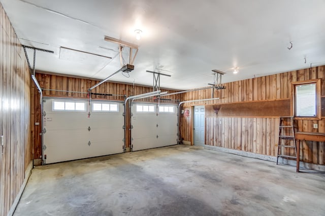 garage featuring a garage door opener and wooden walls