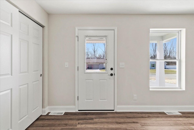 entryway with dark wood finished floors, a healthy amount of sunlight, and baseboards