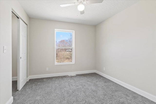 unfurnished bedroom with a closet, carpet flooring, a textured ceiling, and baseboards