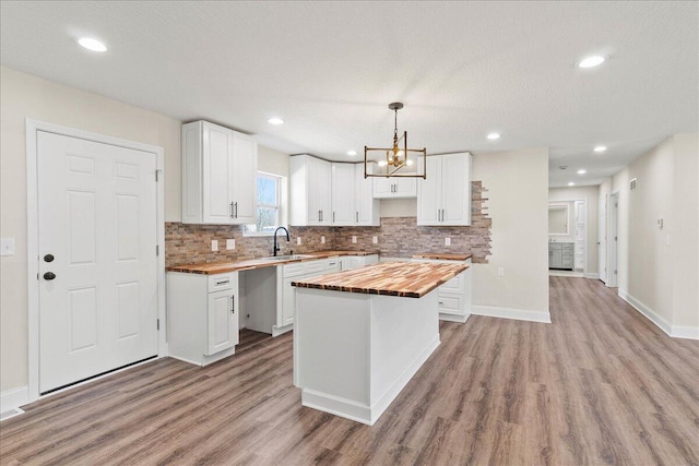 kitchen featuring a sink, light wood-type flooring, decorative backsplash, and butcher block counters