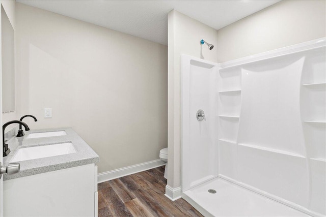 full bathroom featuring a shower stall, baseboards, toilet, wood finished floors, and a sink