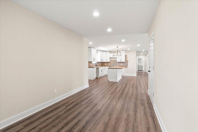 unfurnished living room with a sink, baseboards, and wood finished floors