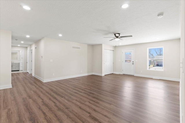 unfurnished living room with visible vents, baseboards, dark wood-type flooring, and a ceiling fan