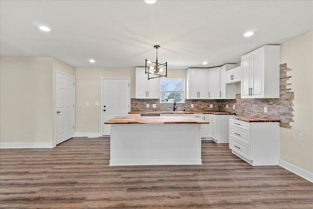 kitchen with a sink, wooden counters, dark wood-style floors, and a center island