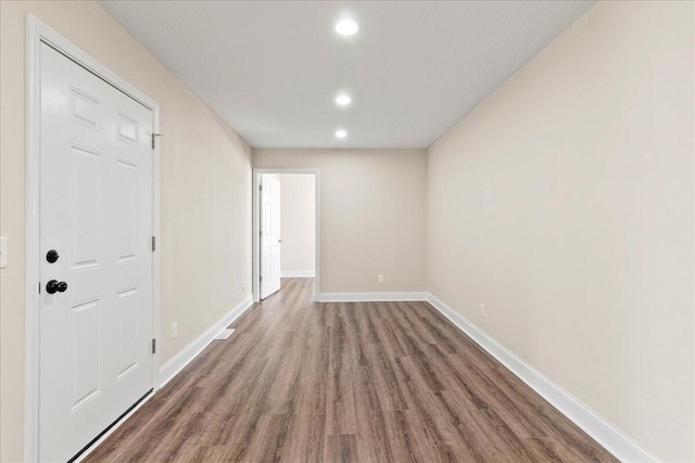 empty room with recessed lighting, baseboards, and wood finished floors