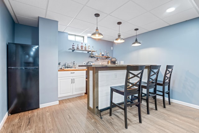 5175 Locust Post Ln, Columbus, OH 43230 - indoor wet bar with freestanding refrigerator, light wood finished floors, decorative light fixtures, and a drop ceiling