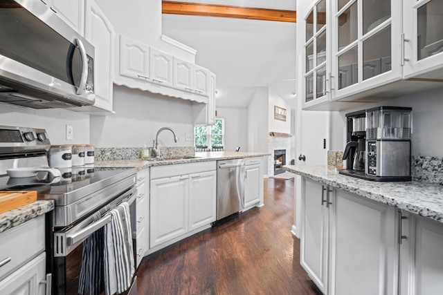 5175 Locust Post Ln, Columbus, OH 43230 - kitchen featuring stainless steel appliances, dark wood-type flooring, a warm lit fireplace, glass insert cabinets, and light stone counters