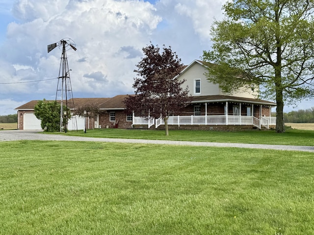 view of front of home featuring a porch, a garage, a front lawn, and gravel driveway
