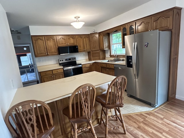 5151 Pheasant St, Lima, OH 45807 - kitchen featuring appliances with stainless steel finishes, a peninsula, light countertops, decorative backsplash, and a kitchen bar