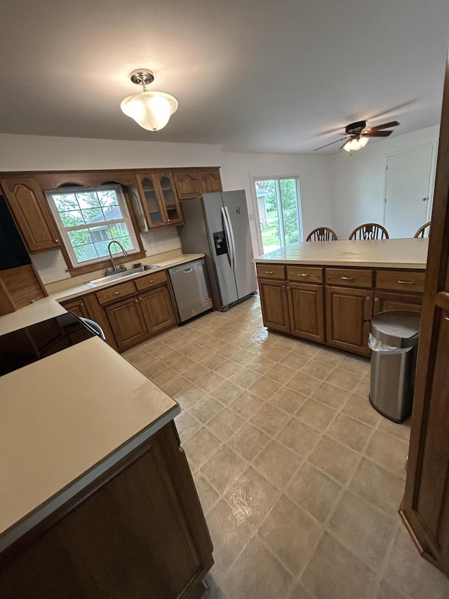 5151 Pheasant St, Lima, OH 45807 - kitchen with appliances with stainless steel finishes, light countertops, ceiling fan, glass insert cabinets, and brown cabinetry