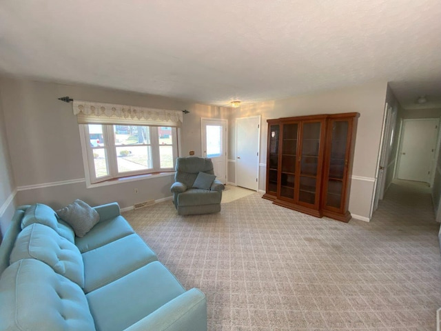 living room with visible vents, light colored carpet, and baseboards