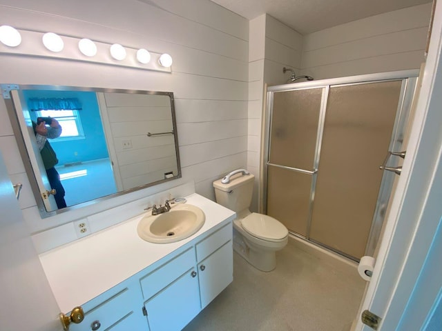 bathroom featuring vanity, a shower stall, toilet, and wood walls