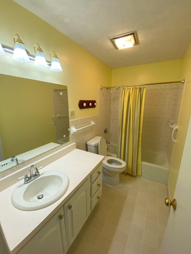 bathroom with toilet, vanity, shower / bath combo, wainscoting, and a textured ceiling