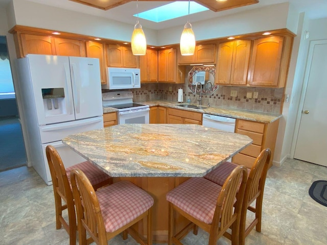 kitchen featuring white appliances, a sink, a kitchen breakfast bar, tasteful backsplash, and a center island