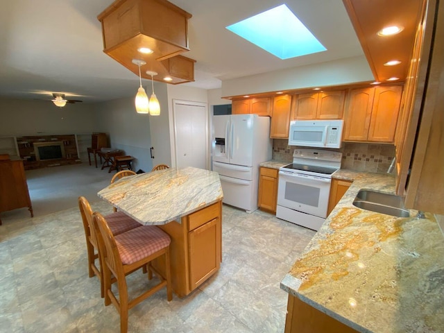 kitchen with a fireplace, a skylight, a kitchen breakfast bar, white appliances, and a sink