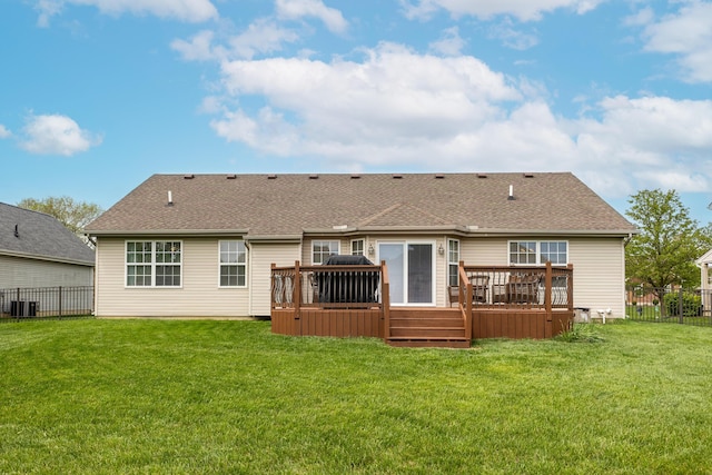 back of property featuring a fenced backyard, roof with shingles, a lawn, and a deck