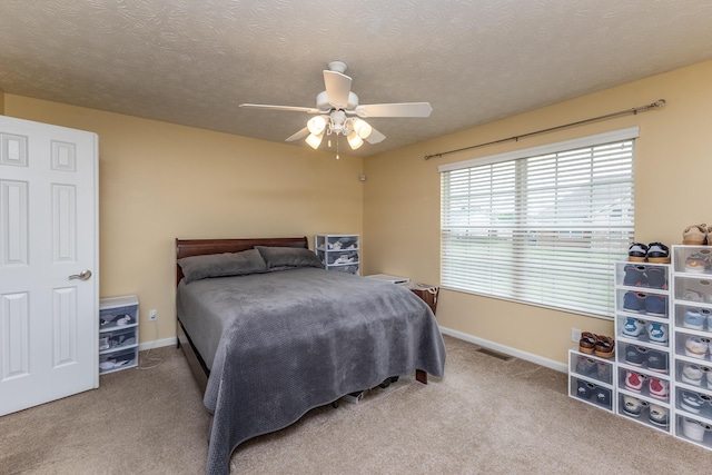 carpeted bedroom featuring baseboards, ceiling fan, a textured ceiling, and visible vents