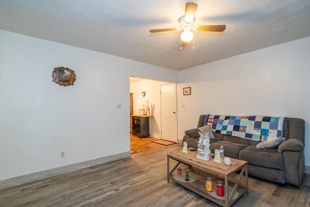 living area with baseboards, a ceiling fan, and wood finished floors