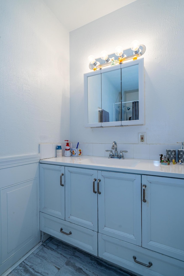 bathroom with marble finish floor, a wainscoted wall, and vanity