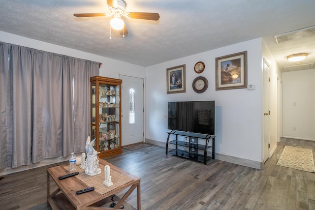 living room with a textured ceiling, wood finished floors, a ceiling fan, visible vents, and baseboards