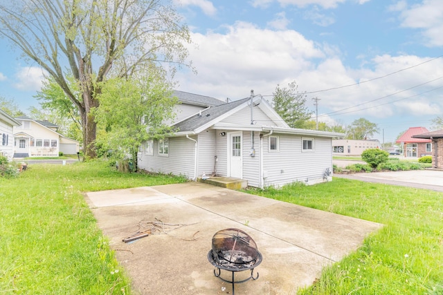 rear view of house featuring an outdoor fire pit, a yard, a patio, and roof with shingles