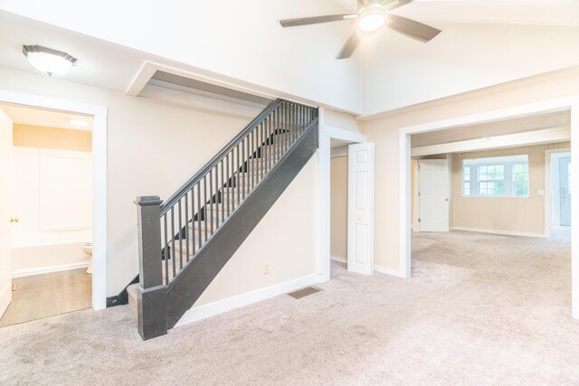 stairs with carpet floors, ceiling fan, and baseboards